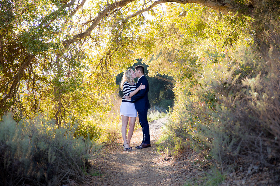 couple kissing under a natural tree arch