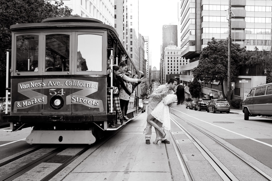 romantic downtown engagement photo with cable car - people cheering at the kiss couple