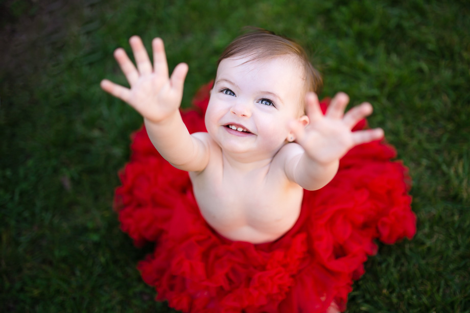 cute baby girl in a fluffy red tutu waving at the camera