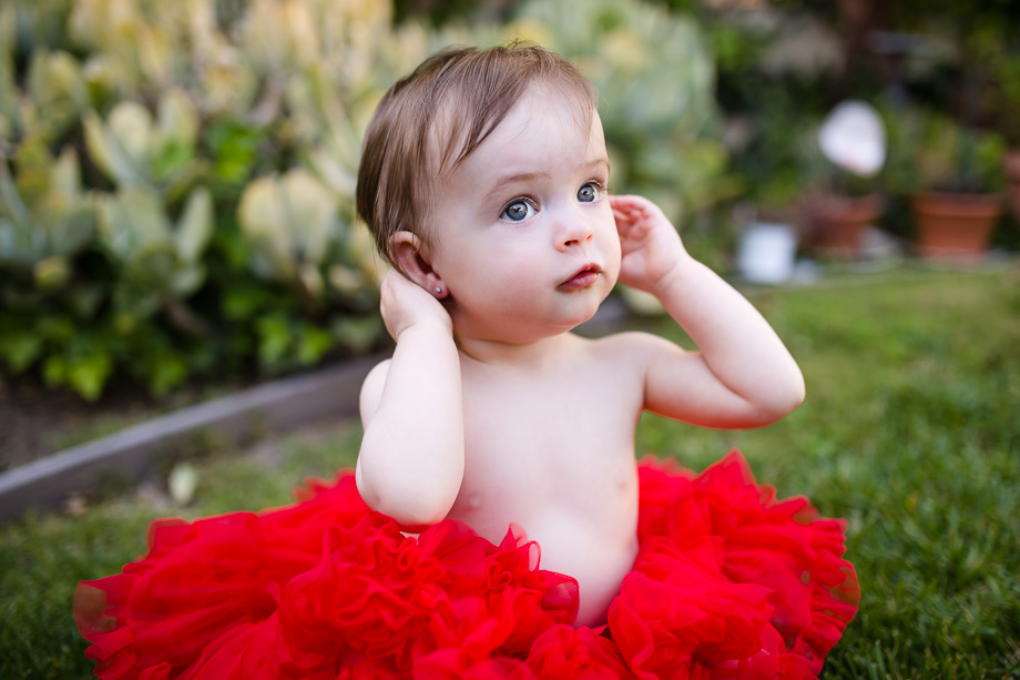 adorable baby girl in a red tutu before the cake smash