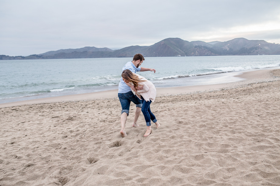 playful couple playing water on Baker Beach - cute San Francisco engagement photo