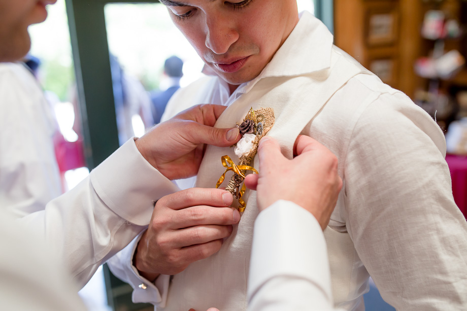 groom pinning the boutonniere handmade by the bride