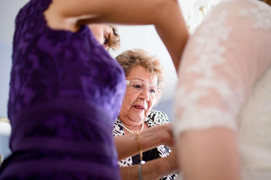 grandma zipping up the wedding dress for the bride
