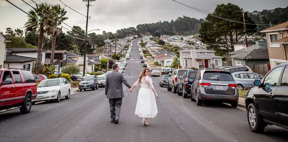 a stunning photo of bride and groom walking in front of their house