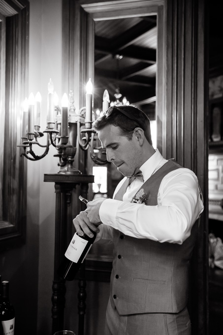 groom opening up a wine bottle by hand