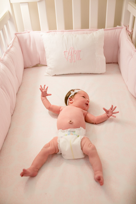 one week old cute baby girl in her pink crib