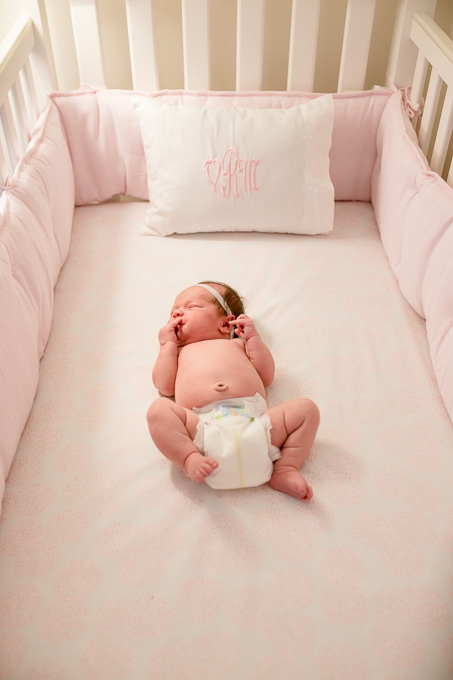 7 day old cute baby girl sleeping in her pink crib