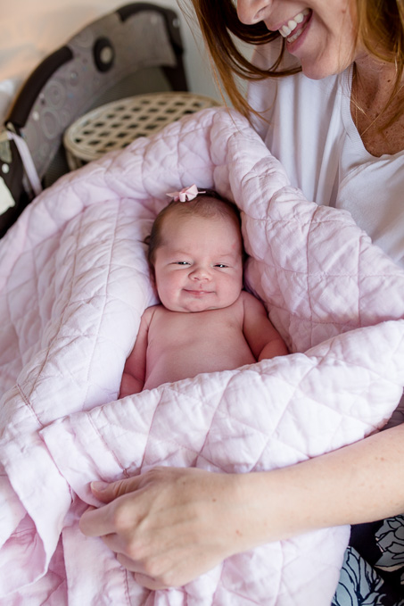 one week old newborn baby girl smiling to the camera