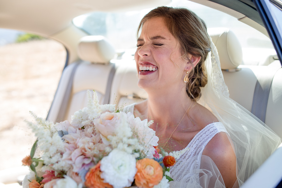 bride laughing in the car before wedding ceremony
