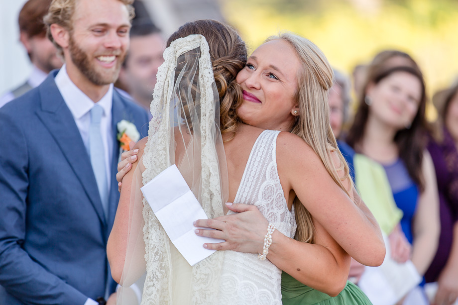 bridesmaid giving sister-in-law a warm hug during the wedding ceremony