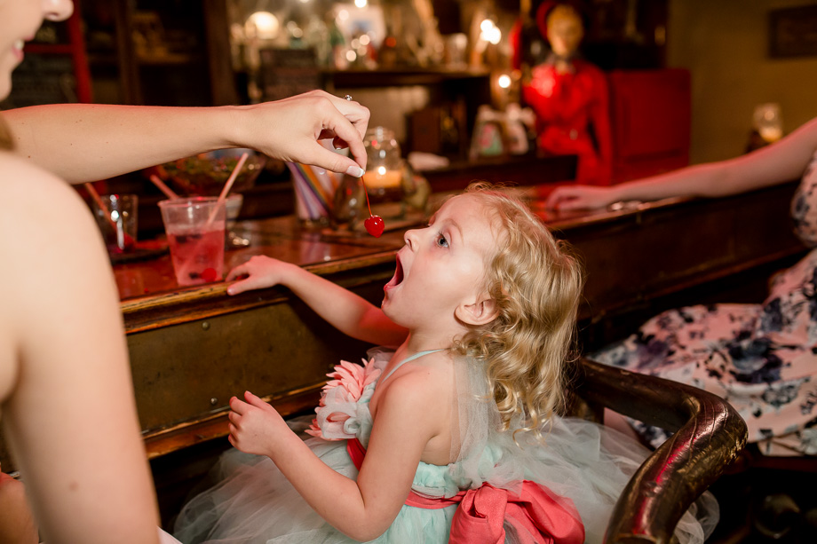 adorable hungry flower girl at the bar eating cherries