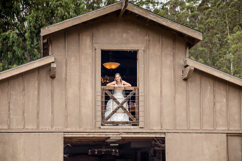 beautiful bride peeking out from the old rustic farmhouse