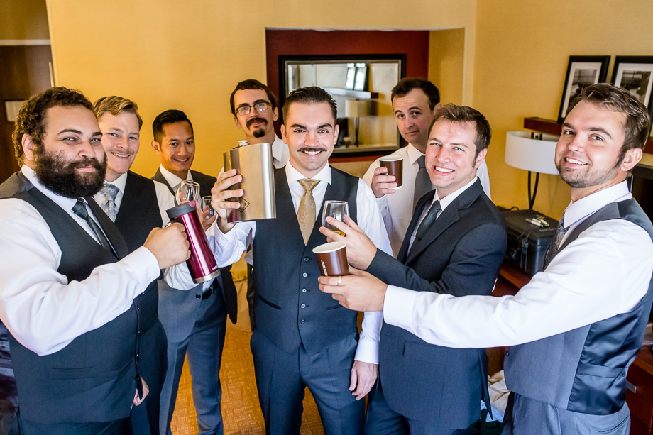 groom holding a giant flask as groomsmen gifts