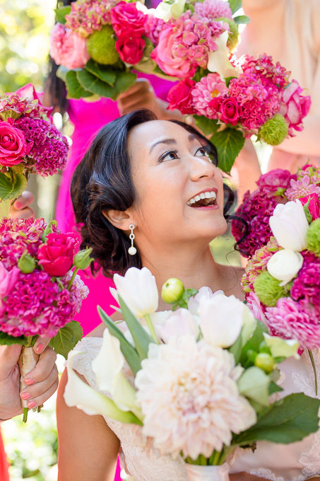 colorful and bright portrait of the bride framed by bridesmaids bouquets
