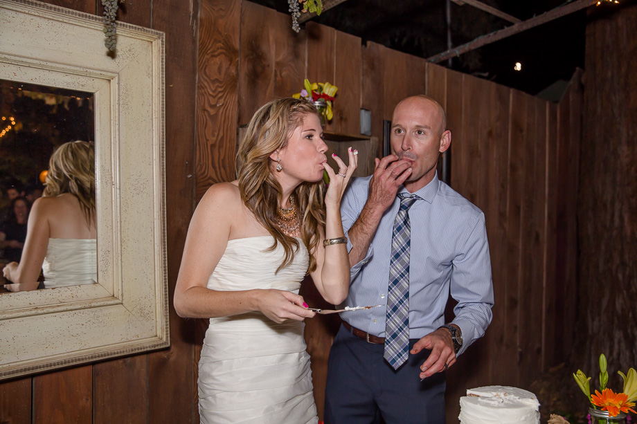 cute moment of bride and groom sucking fingers at the same time after cutting the wedding cake - san jose wedding