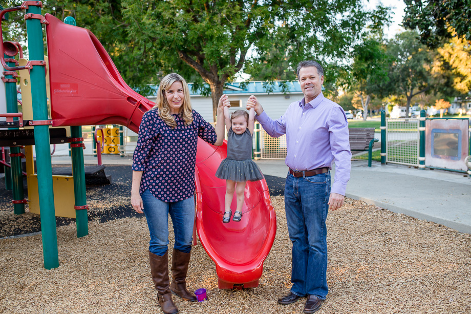 parents with daughter on playground slide