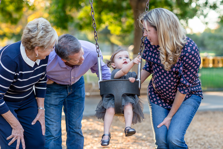 toddler sitting inside a swing surrounded by loved ones - san jose family photographer