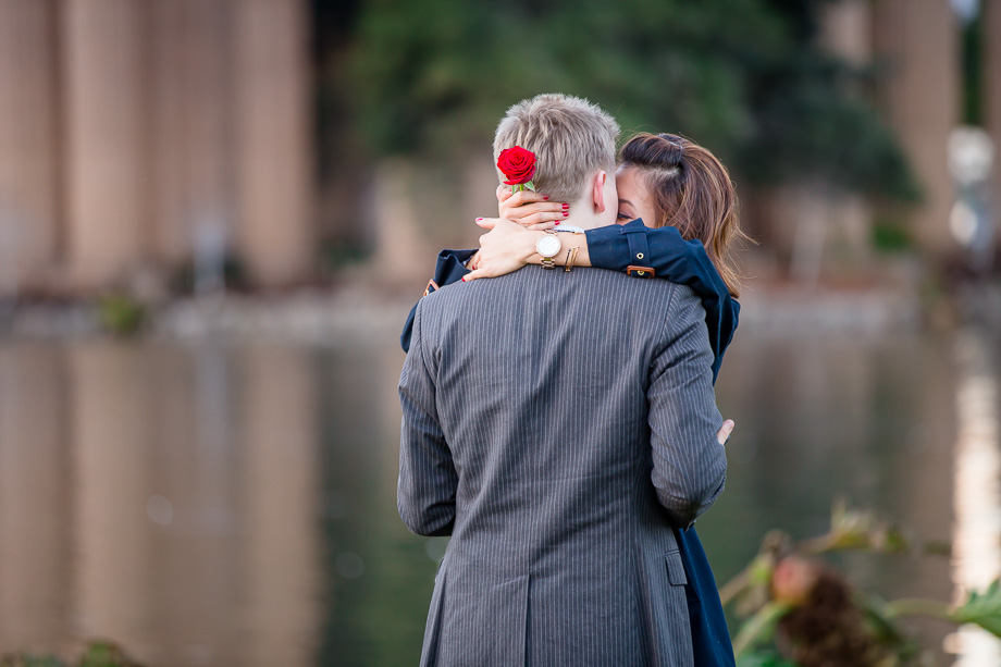 kissing after surprise proposal, holding red rose