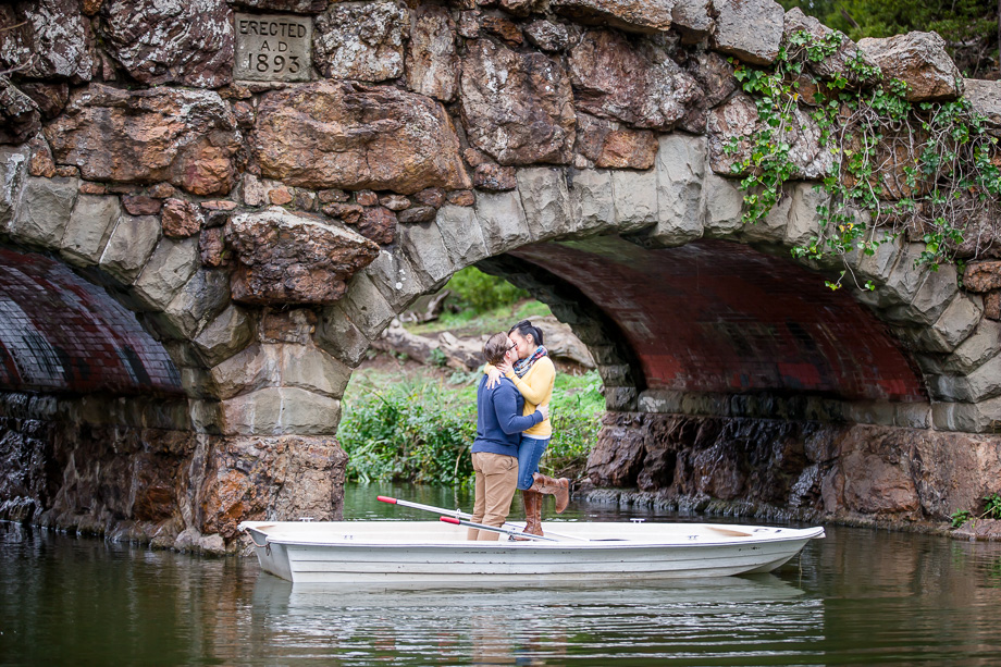 romantic kissing photo on a boat under Stow Lake stone arch bridge