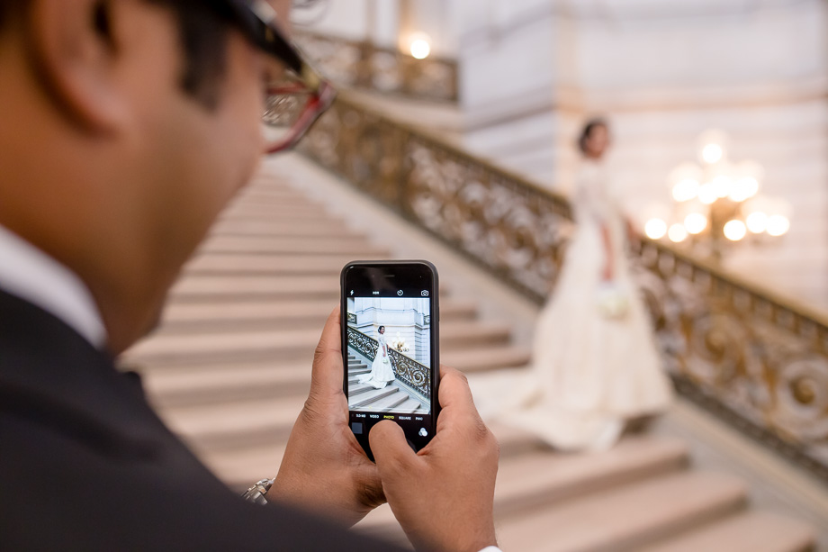 groom taking a cute photo of bride on their wedding day at San Francisco City Hall