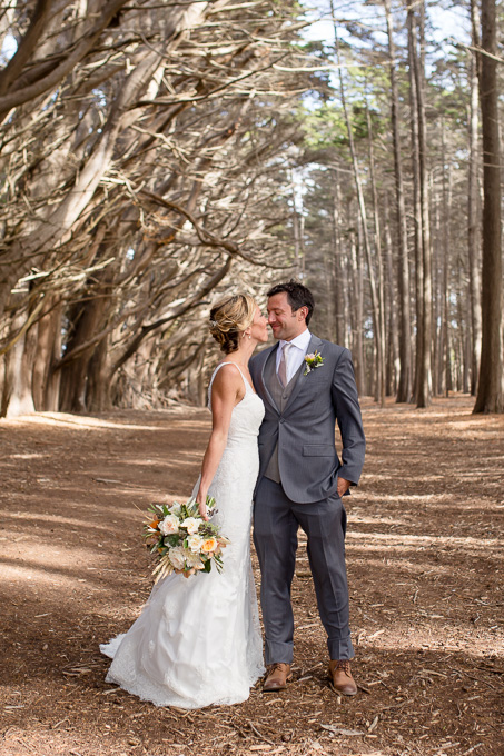 bride and groom kissing under cypress tree arch