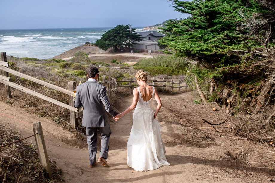 romantic candid photo of bride and groom walking along a beachside Half Moon Bay hiking trail