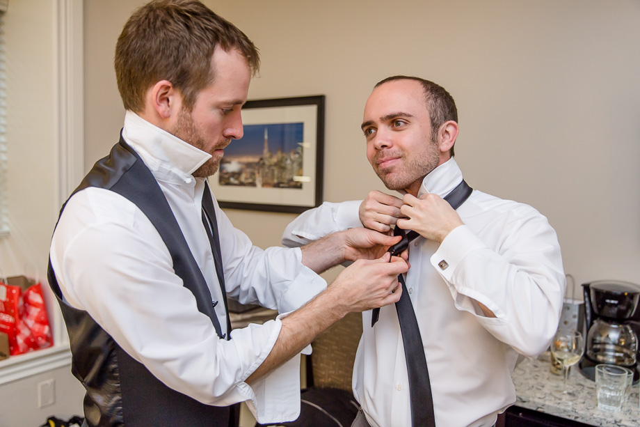 best man tying the tie for the groom