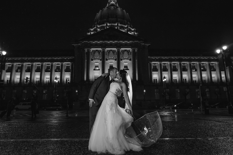 a romantic bride and groom photo in the rain in the dark in front of San Francisco City Hall