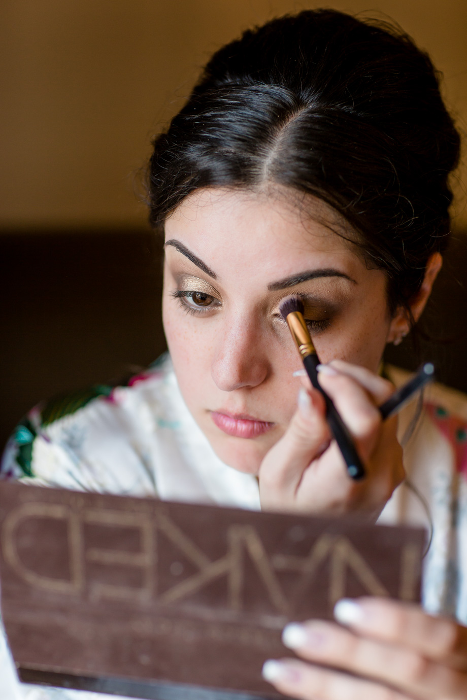 bride performing final touch ups on her eye makeup