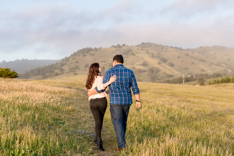 pretty couple walking along a rolling grassy field