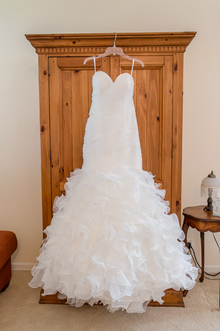 beautiful white wedding dress hanging on a dresser