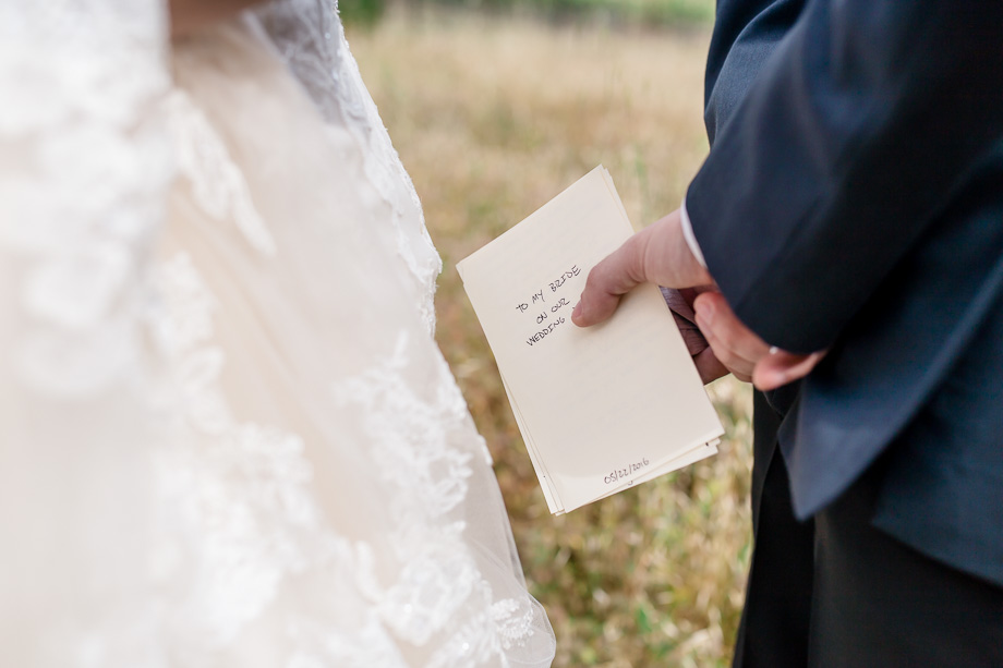groom holding a hand written letter to the bride behind his back