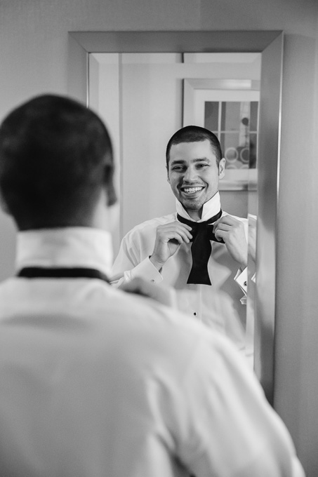 groom getting ready tying tie in mirror