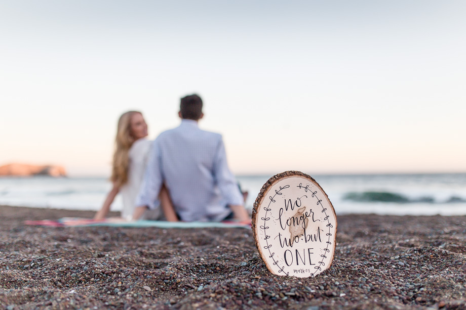 sunset engagement photo with a wooden sign that says no longer two but one