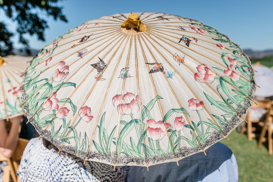 newlywed provided their guests with floral paper umbrellas for them to shade during the ceremony