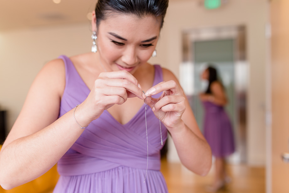 bridesmaid helping the bride to untangle her necklace