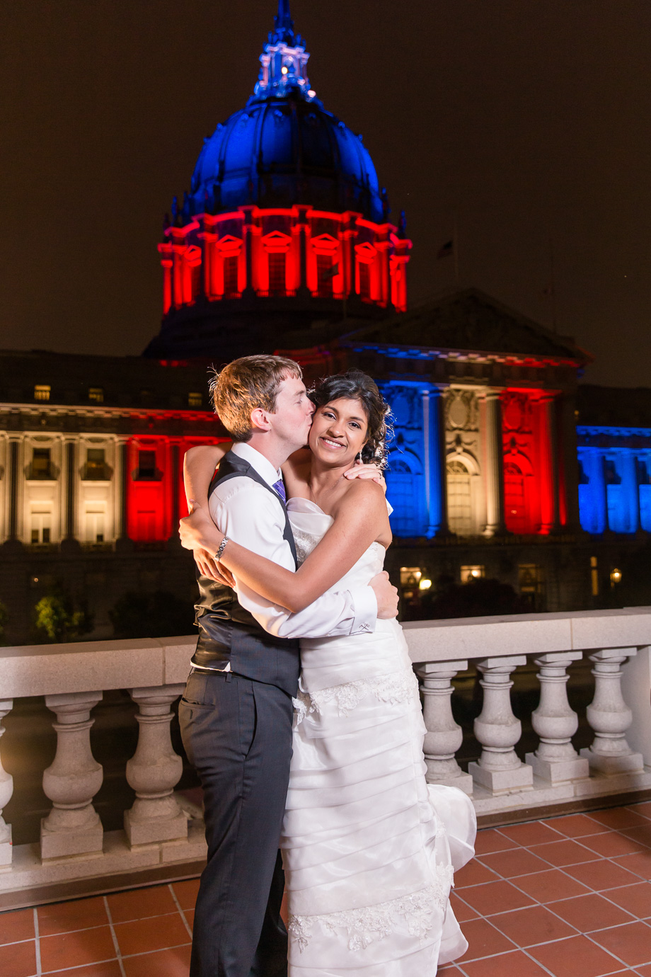 a gorgeous night shot of the bride and groom and SF city hall from the War Memorial balcony