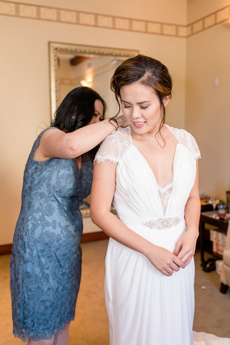 mom helping bride to lace up her dress