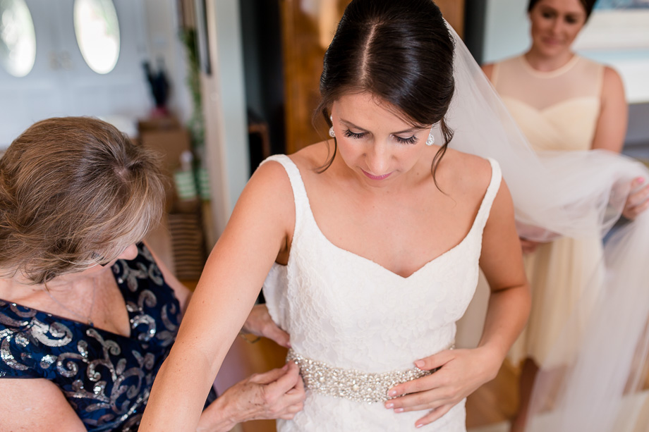 mom sewing the bridal sash onto the dress