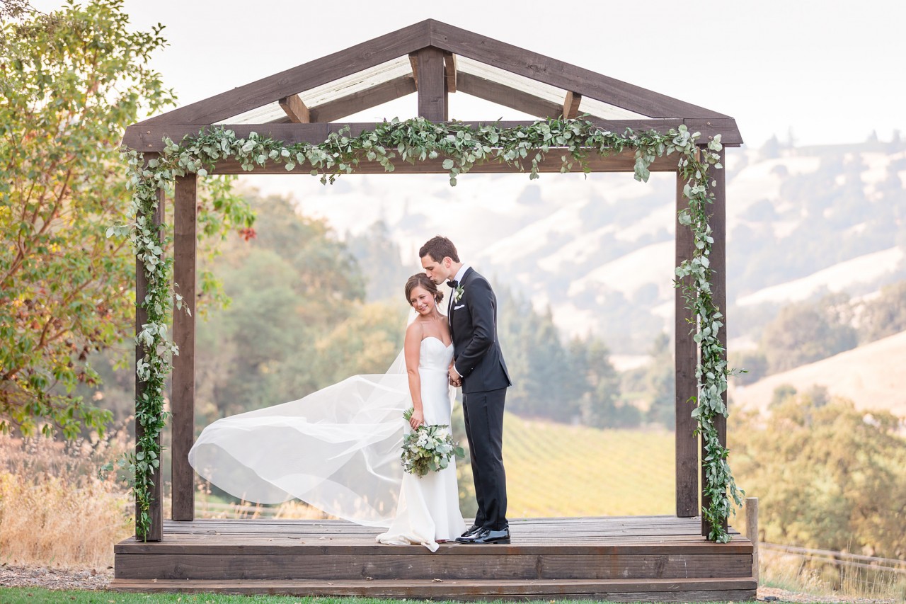 wooden ceremony arbor with light leafy decor