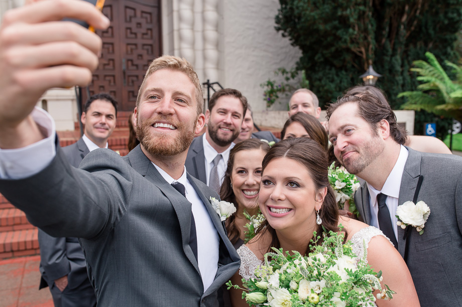 entire bridal party taking a selfie outside the church