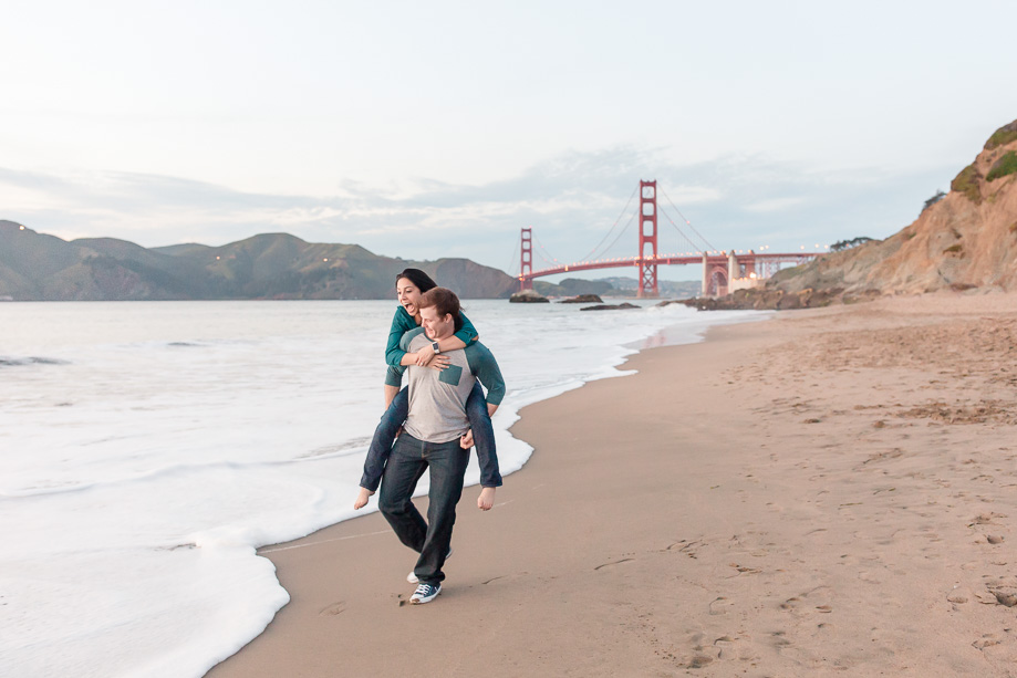 fun romantic piggyback ride incoming wave at the beach near Golden Gate Bridge