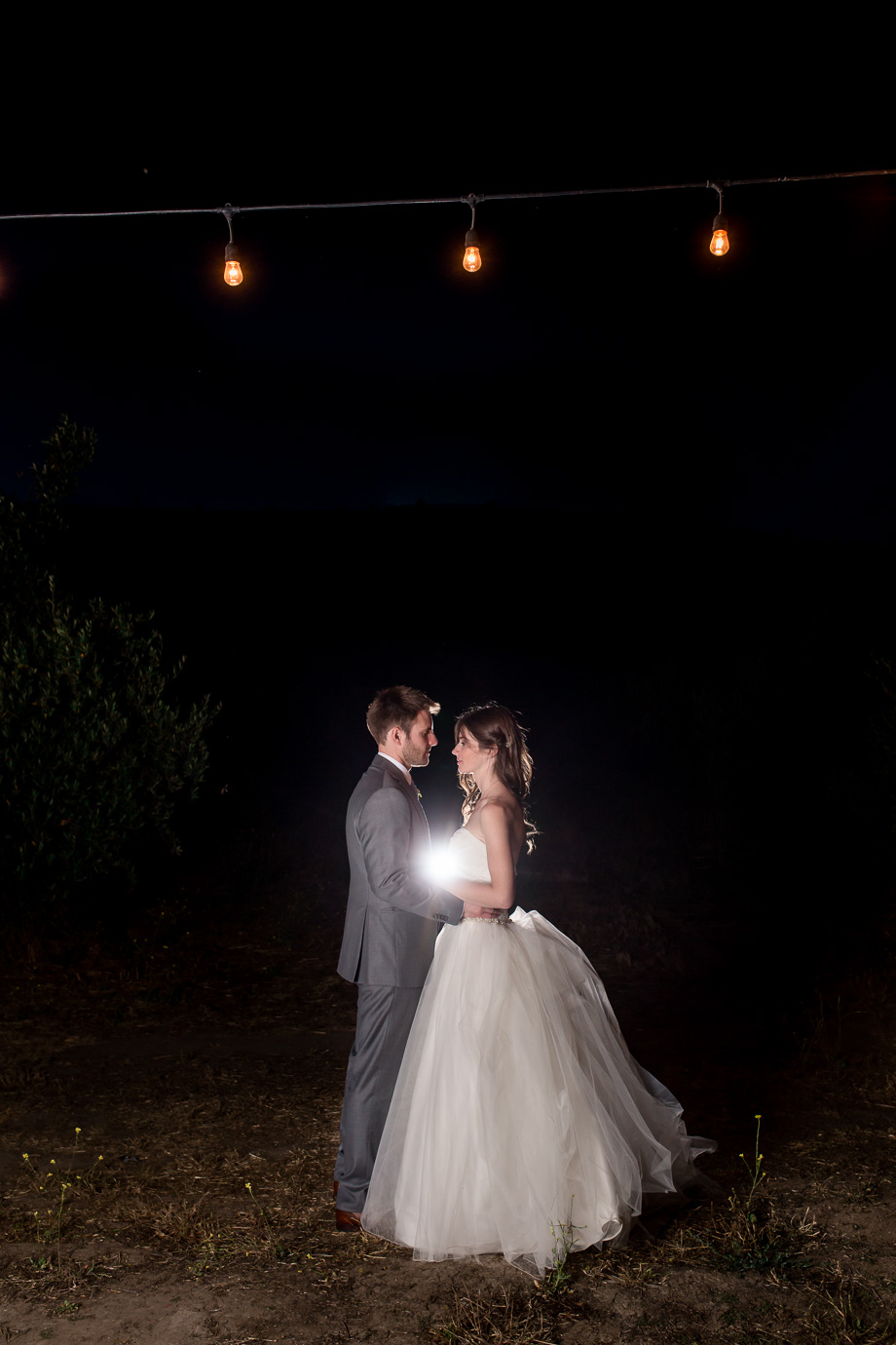 a night shot of bride and groom under the cafe string lights