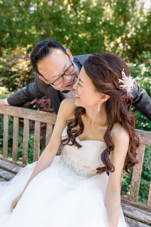 bride and groom smiling at each other on a bench