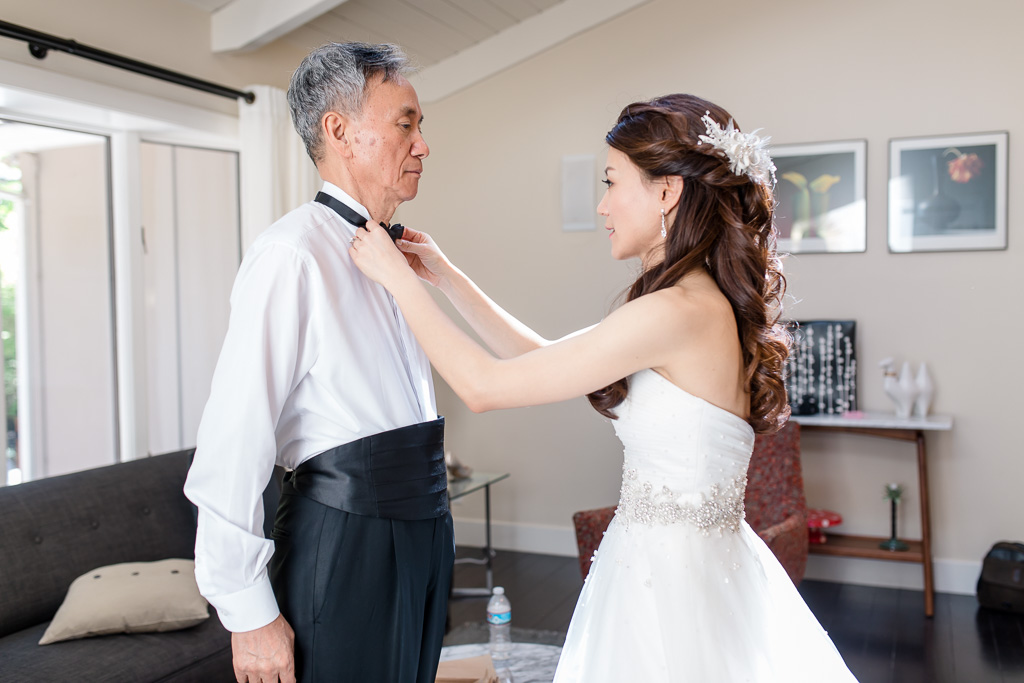 bride putting on bow tie for father