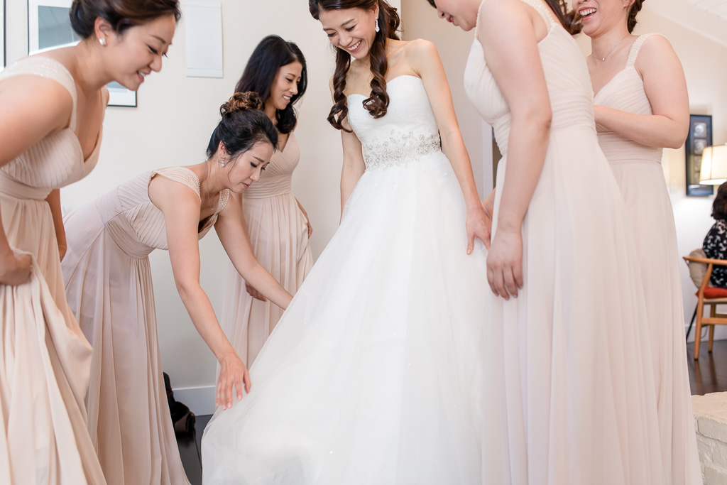 bridesmaids helping to adjust and fit bride's dress