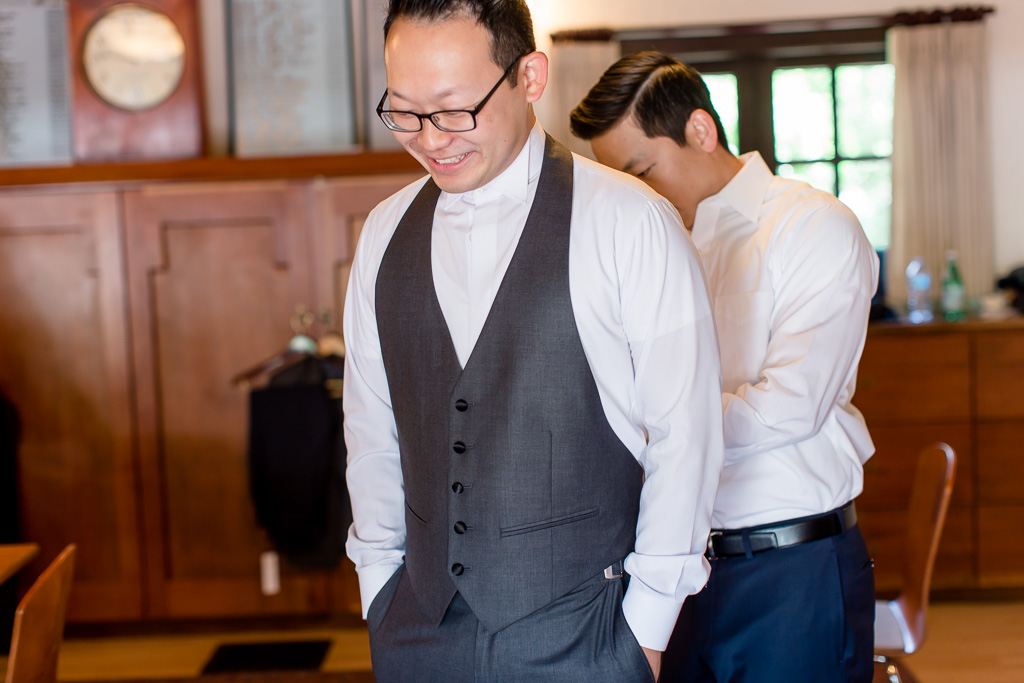 groomsman helping groom with his vest