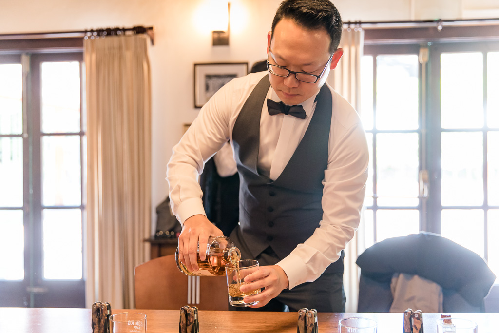groom pouring whiskey for his groomsmen before wedding