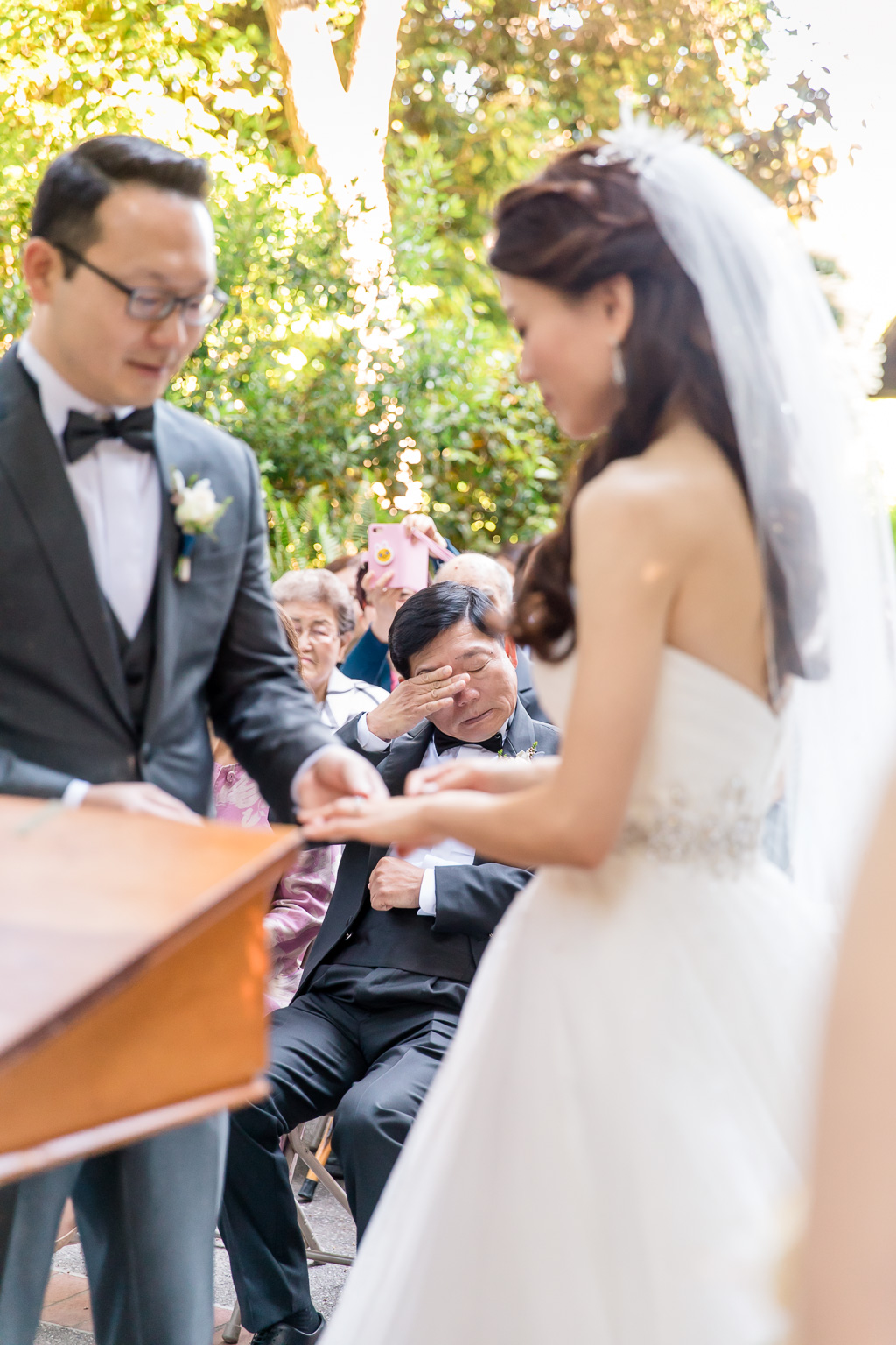 father wiping tears in wedding ceremony audience