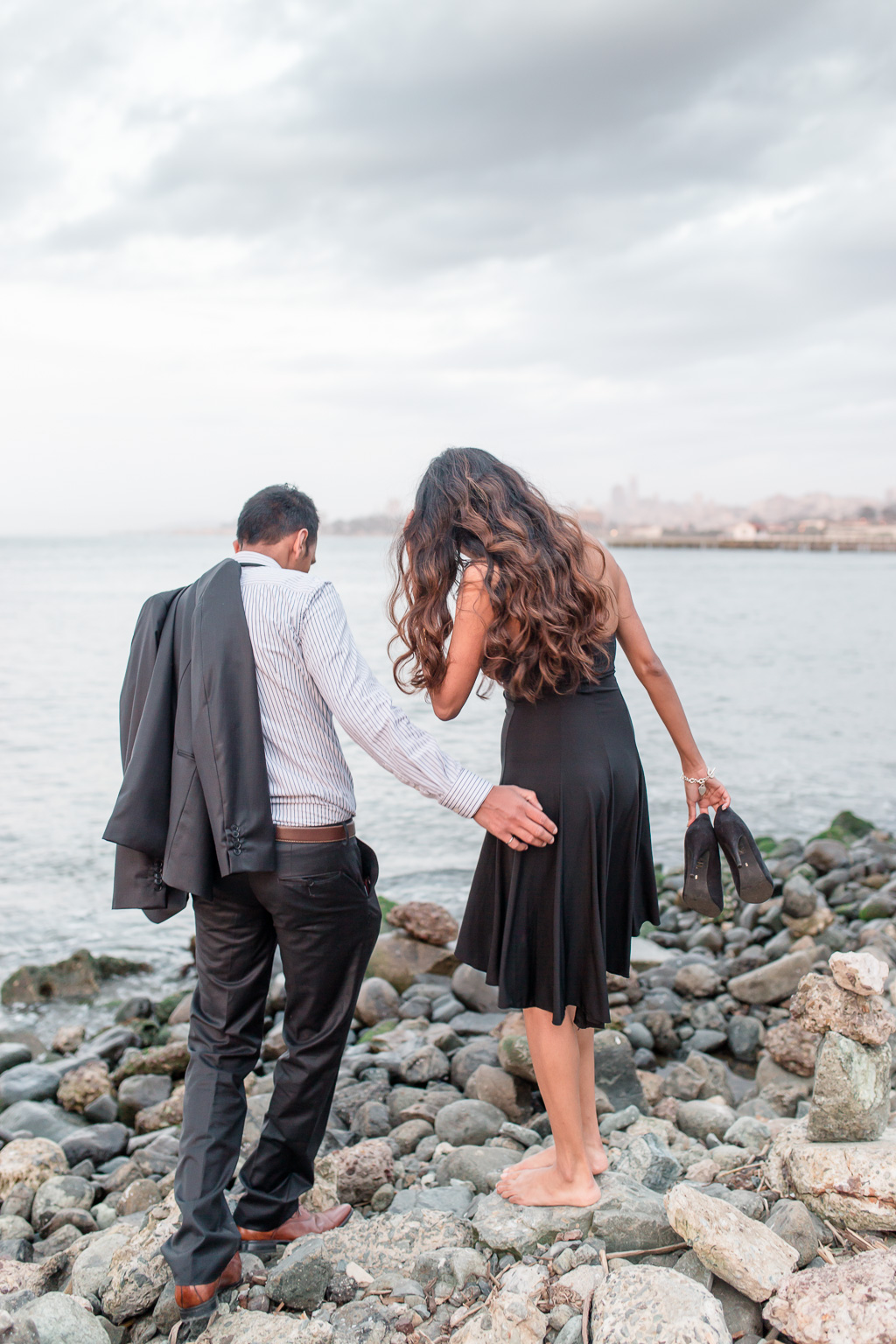 candid moment of the couple walking on the rocks along the San Francisco Bay